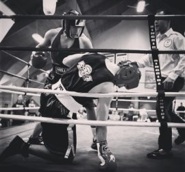 A man in boxing gloves is standing on the ropes.